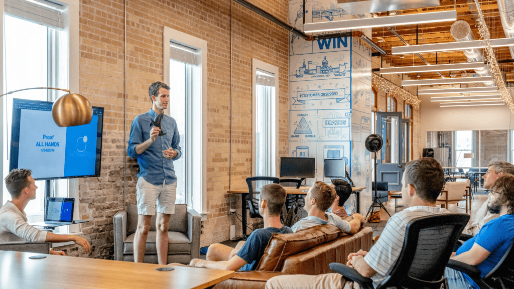 Man presenting to a group in a casual office setting.